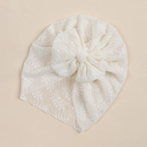 Detail of baby lace bow turban featuring intricate floral patterns and soft mesh texture