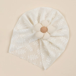 Detail of baby white lace turban hat with a large 3D floral decoration and mesh texture