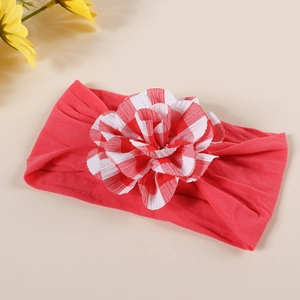 Detail of baby headband featuring large red gingham fabric flower on pink elastic band