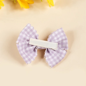 Pink checkered bow hair clip with scalloped edges for babies and newborns in a soft style