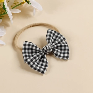 Detailed macro view of baby elastic headband featuring black and white checkered bow tie
