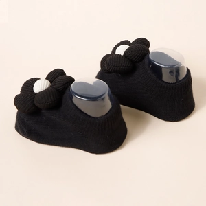 Detail of black knitted baby socks with 3D black and white fabric flower decorations