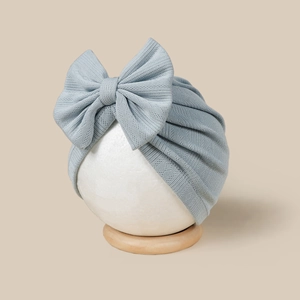Detailed close-up of light blue baby turban hat with a large bow and ribbed knit texture