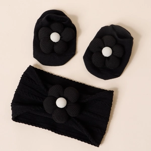 Detail of baby headband and socks set with 3D black flower decor on soft knit fabric