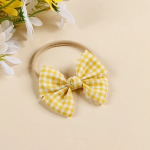 Macro view of a baby headband featuring a yellow and white gingham bow with wavy edges