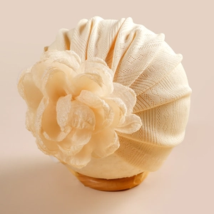 Détail du bonnet turban bébé avec grande fleur 3D et texture tricotée douce en beige