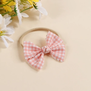 Detailed view of baby headband with pink checkered bow and soft elastic nylon band