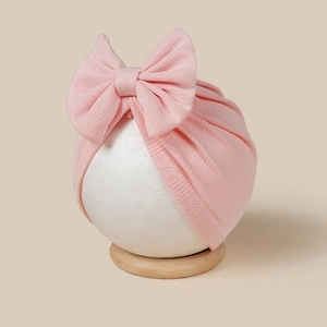 Detail of pink ribbed knit baby turban hat with a soft large bow on a mannequin