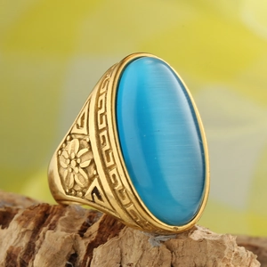 Macro shot of oval blue cat eye stone with detailed golden floral pattern ring
