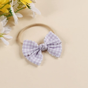 Detail of baby headband featuring purple checkered fabric bow and wave-cut edges