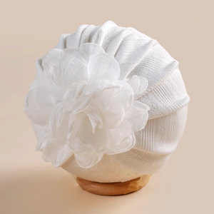 Vue détaillée du bonnet turban blanc pour bébé avec une grande fleur en tulle multicouche