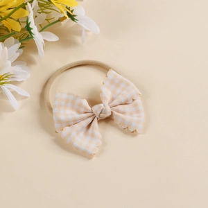 Detail of baby headband featuring cream checkered bow and soft nylon elastic band