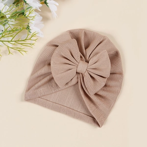 Flat lay of a warm brown waffle knit baby turban hat with a large decorative bow