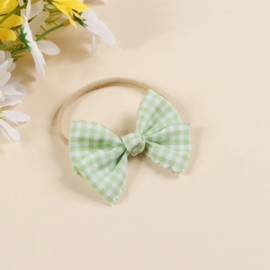 Detail of green and white plaid baby bow headband with soft elastic nylon strap