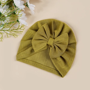 Detail shot of a mustard yellow newborn turban hat with a large bow and knitted texture