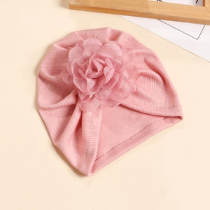 Détail du bonnet turban rose pour bébé en maille côtelée avec une grande fleur en tulle