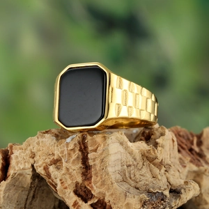 Macro shot of men's gold signet ring with black square stone and textured grid band
