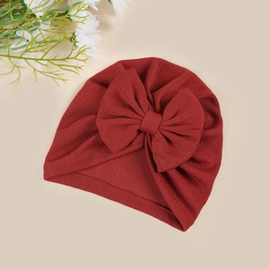 Detail of burgundy ribbed knit baby turban hat with a large decorative bow