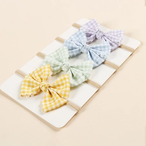 Macro detail of infant gingham bow headbands set in pastel macaron colors with wavy edges