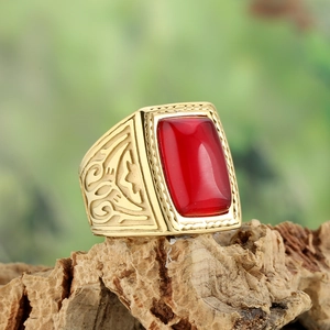 Vintage gold-plated stainless steel ring with rectangular red gemstone on wood