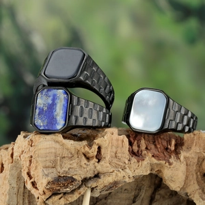Detail of three men's black titanium rings with onyx, lapis and shell on cork base