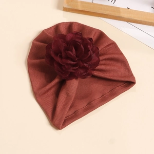 Détail d'un turban pour bébé orné d'une grande fleur 3D sur un tissu en maille côtelée