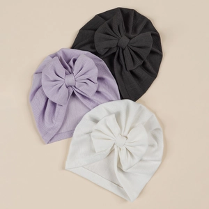 Close-up of jacquard baby bow hats in black, lilac, and white soft ribbed fabric