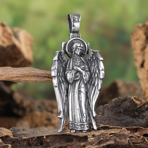 Macro shot of a vintage praying angel pendant with wings on natural wood texture