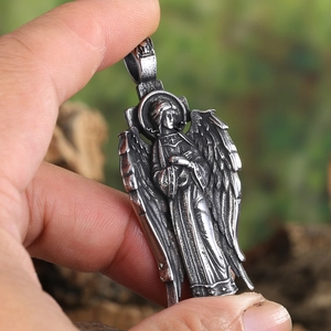 Retro angel relief pendant with detailed wings and holy icon in hand-held macro view