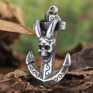 Close-up of vintage stainless steel anchor pendant with skull carving on wood