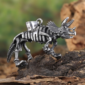 Detailed view of vintage silver triceratops skeleton pendant on a natural wood surface