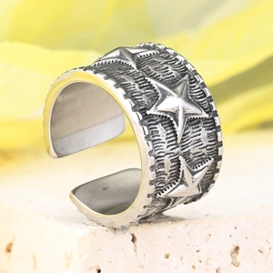 Macro d'une bague large ouverte avec des motifs d'étoiles en relief et un fini argent rétro