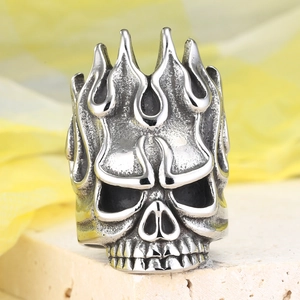 Detail of vintage silver skull ring with flame carving on a stone surface