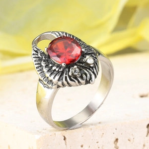 Detalle macro de anillo de águila vintage con gran cristal rojo y plumas de acero