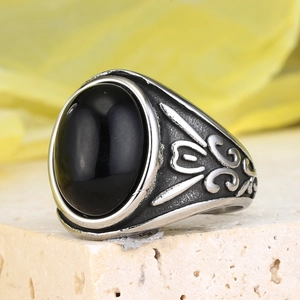 Macro view of retro stainless steel ring with black gemstone and engraved scroll texture