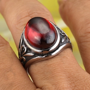 Close-up of a vintage steel ring with an oval red gemstone and floral engravings