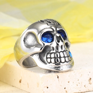 Dettaglio macro di un anello teschio punk con occhi di zircone blu e croce incisa