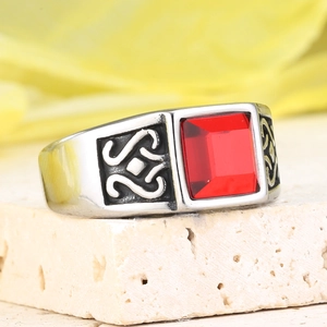 Macro d'une bague vintage en acier inoxydable avec pierre rouge carrée et gravures noires
