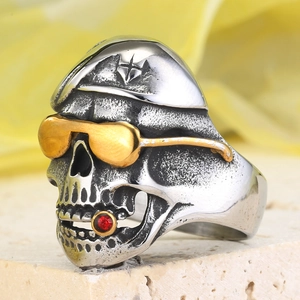 Makroaufnahme: Vintage Totenkopfring mit goldener Sonnenbrille und rotem Zirkonstein