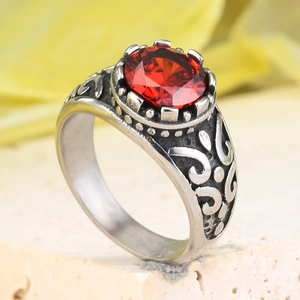 Detail view of vintage stainless steel ring with red oval gemstone and ornate carvings