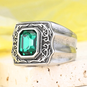 Dettaglio ravvicinato di anello vintage con gemma verde e incisioni stile barocco