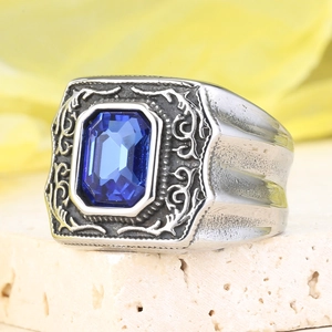 Dettaglio macro dell'anello da uomo in acciaio al titanio con gemma blu e decori a rilievo
