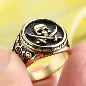 Detail of golden pirate skull ring with cross swords and steering wheel engraving
