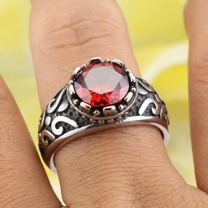 Macro shot of retro crown-set round red gemstone ring with ornate silver scrollwork carving
