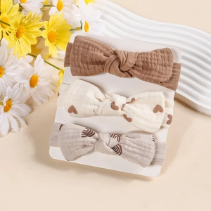 Detailed view of three cotton bow headbands for babies in brown and heart patterns