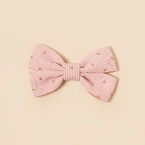 Détail d'un nœud papillon en velours côtelé rose avec pois dorés scintillants