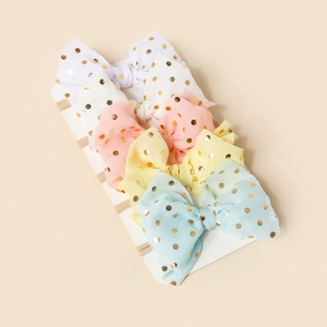 Detail of four-piece soft nylon baby headbands with shimmering gold polka dot mesh bows