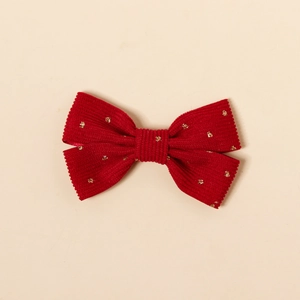 Détail d'une pince à cheveux en velours côtelé rouge avec motifs étoiles dorées