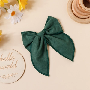 Détail d'un nœud papillon en lin vert foncé avec bords cousus sur fond esthétique