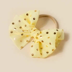 Close-up of baby nylon headband with sequined yellow mesh bow and golden dots